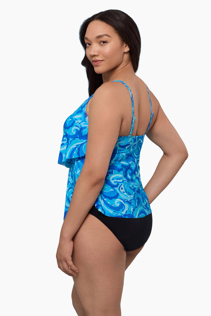 Woman turned left wearing a tiered tankini top with an abstract blue pattern