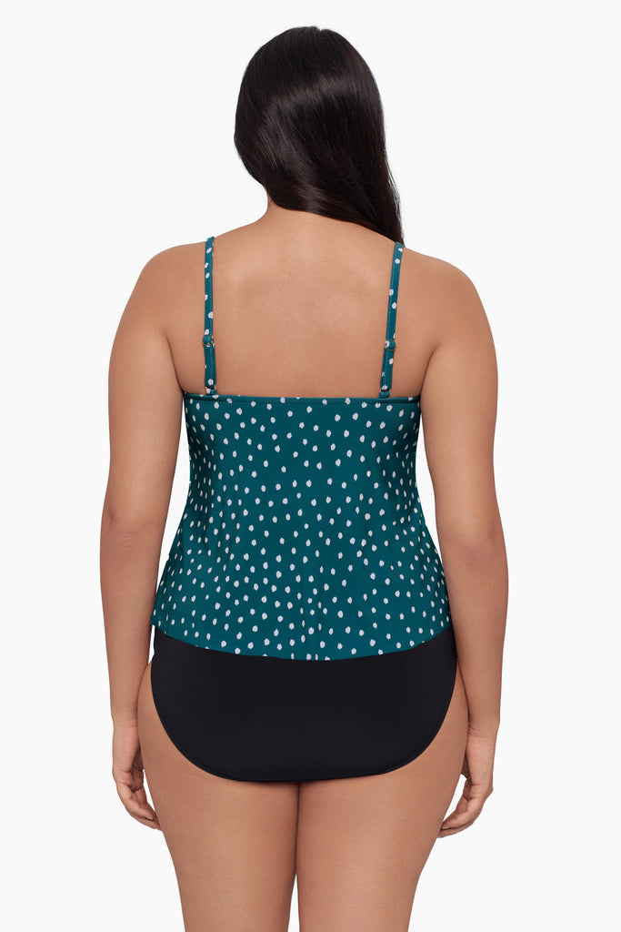 Woman turned away wearing a tankini top with a white polka dot pattern
