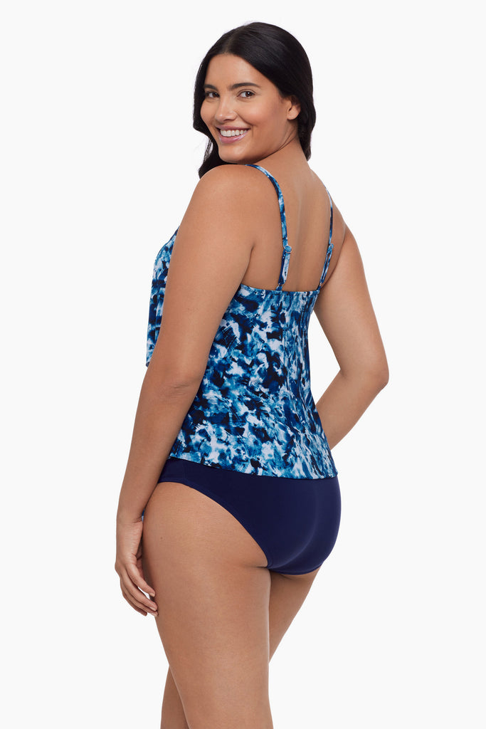 Woman turned left  wearing a tiered tankini top with a blue tie dye print
