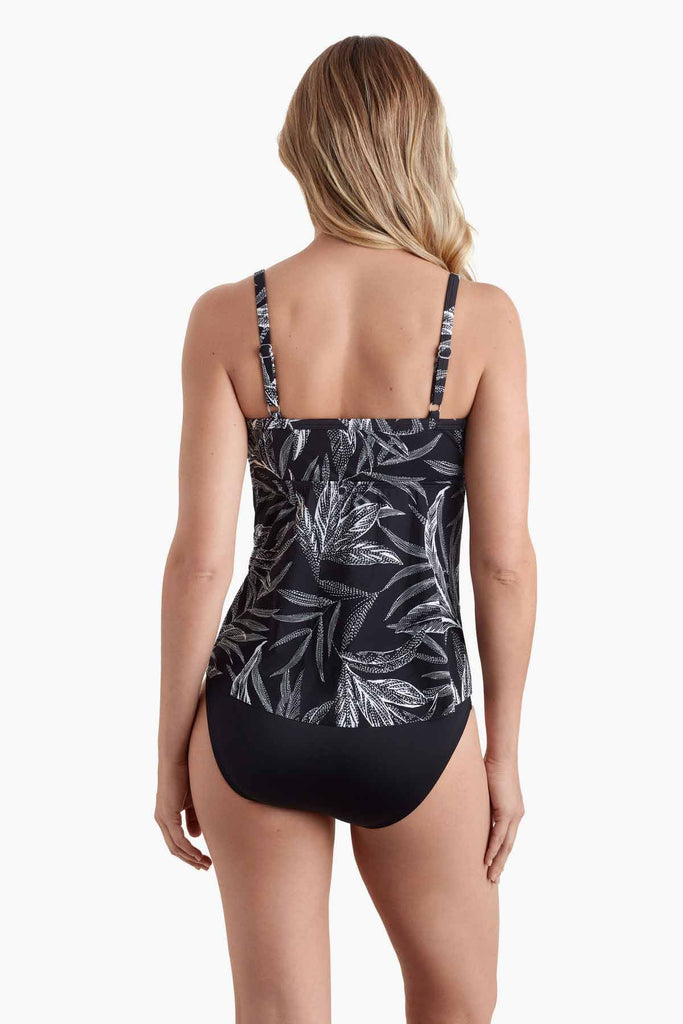 Woman faced away wearing a tankini top with black and white palm leave print