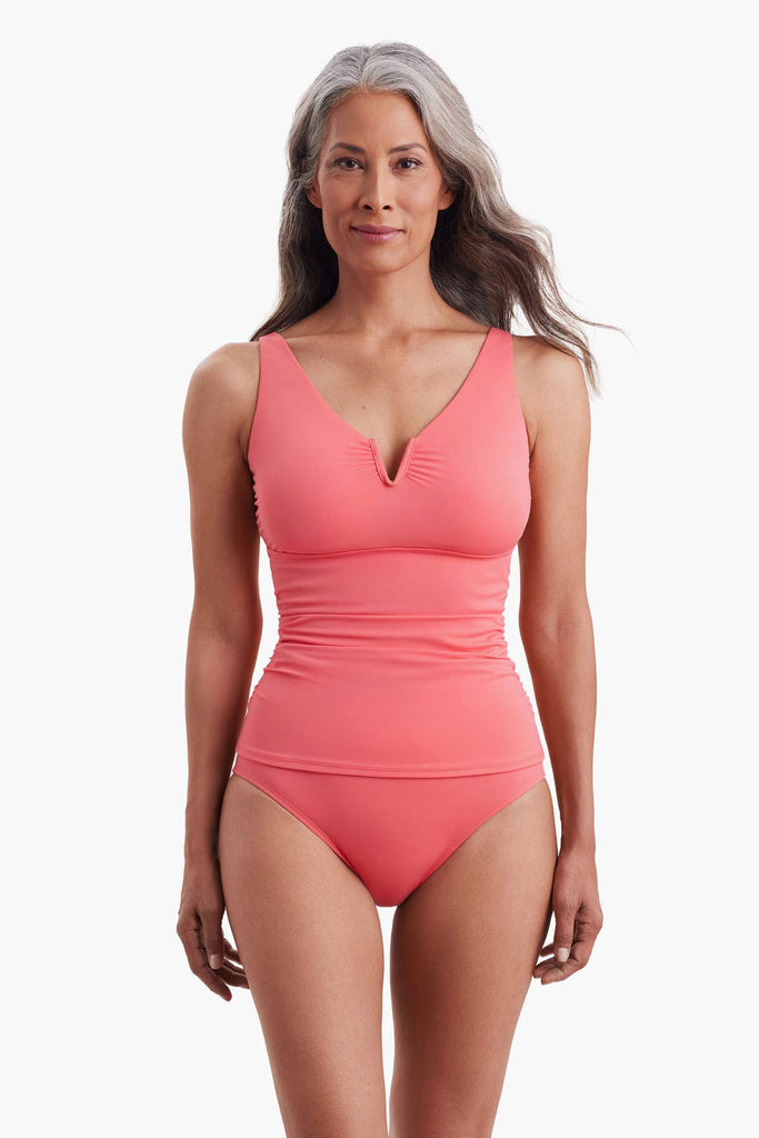 Woman wearing a coral pink one-piece swimsuit with a sweetheart neckline