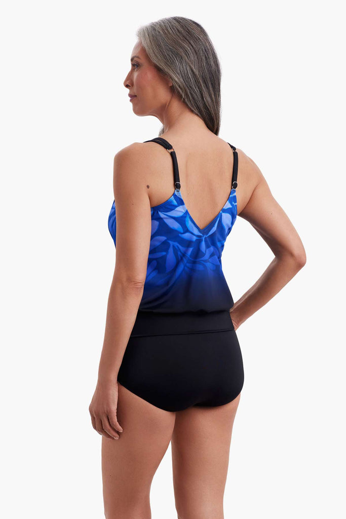 Woman faced left wearing a tankini top with a faded blue floral print 