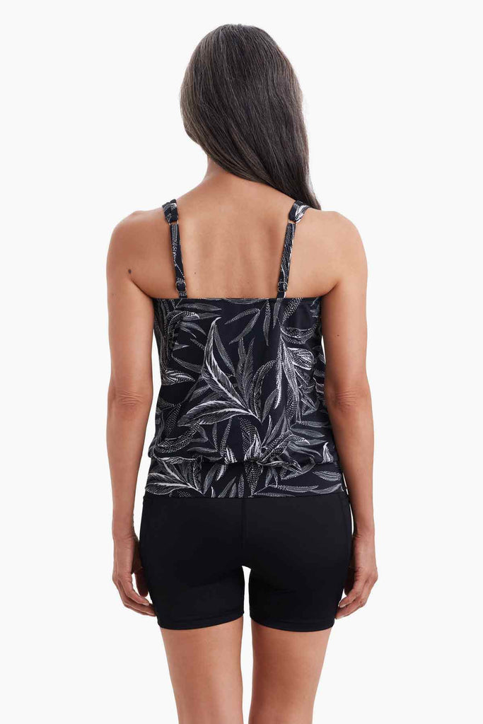 Woman turned away wearing a tankini top with a black and white palm leaf print