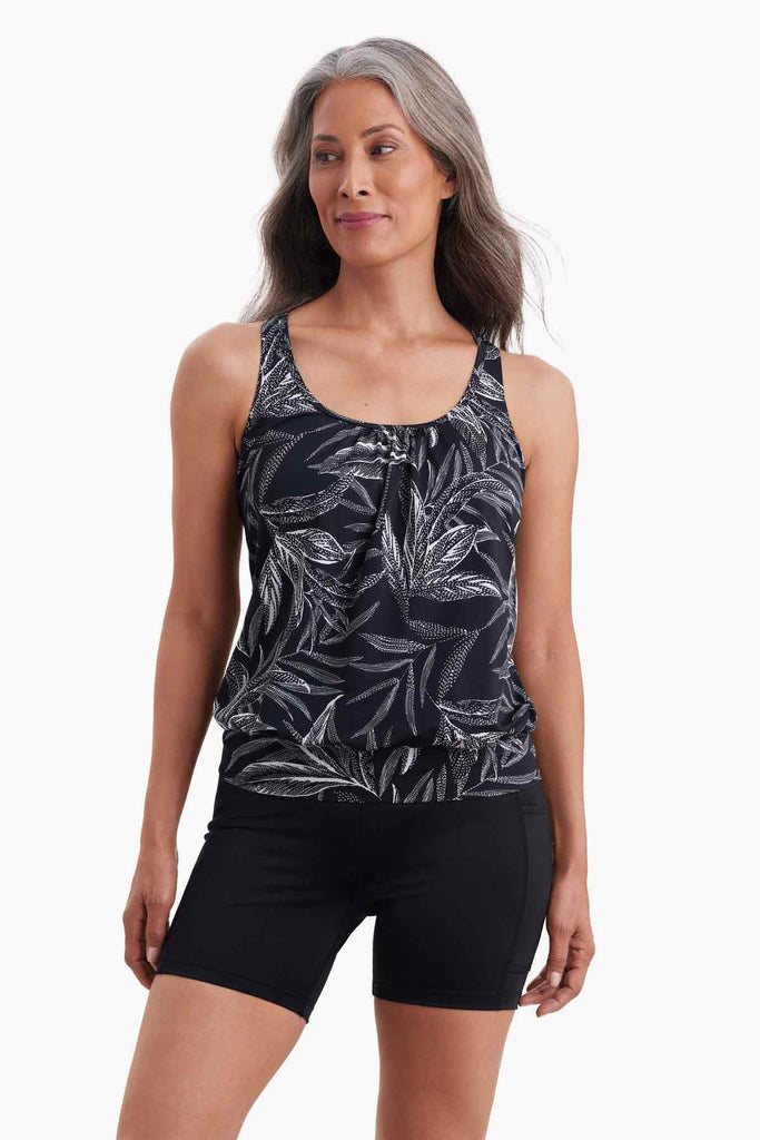 Woman wearing a shirred blouson tankini top with a black and white palm leaf print
