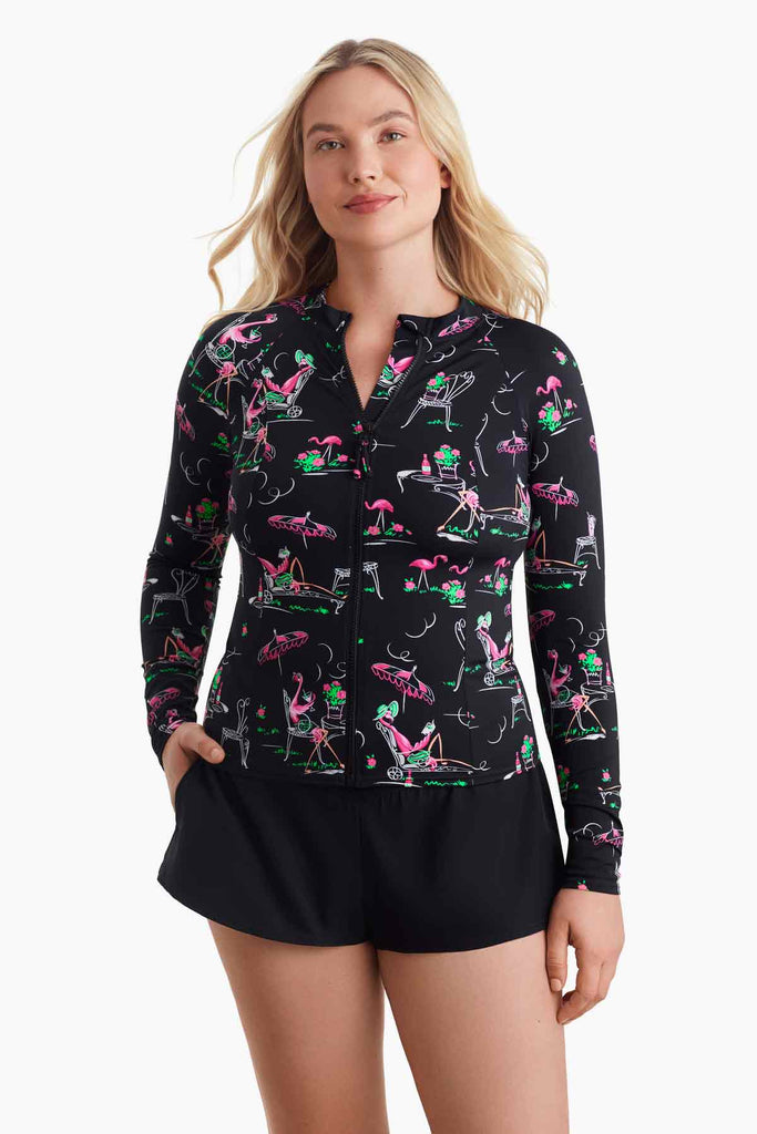 Woman wearing a flamingo printed sun shirt with a zipper in the front with her hand in pocket