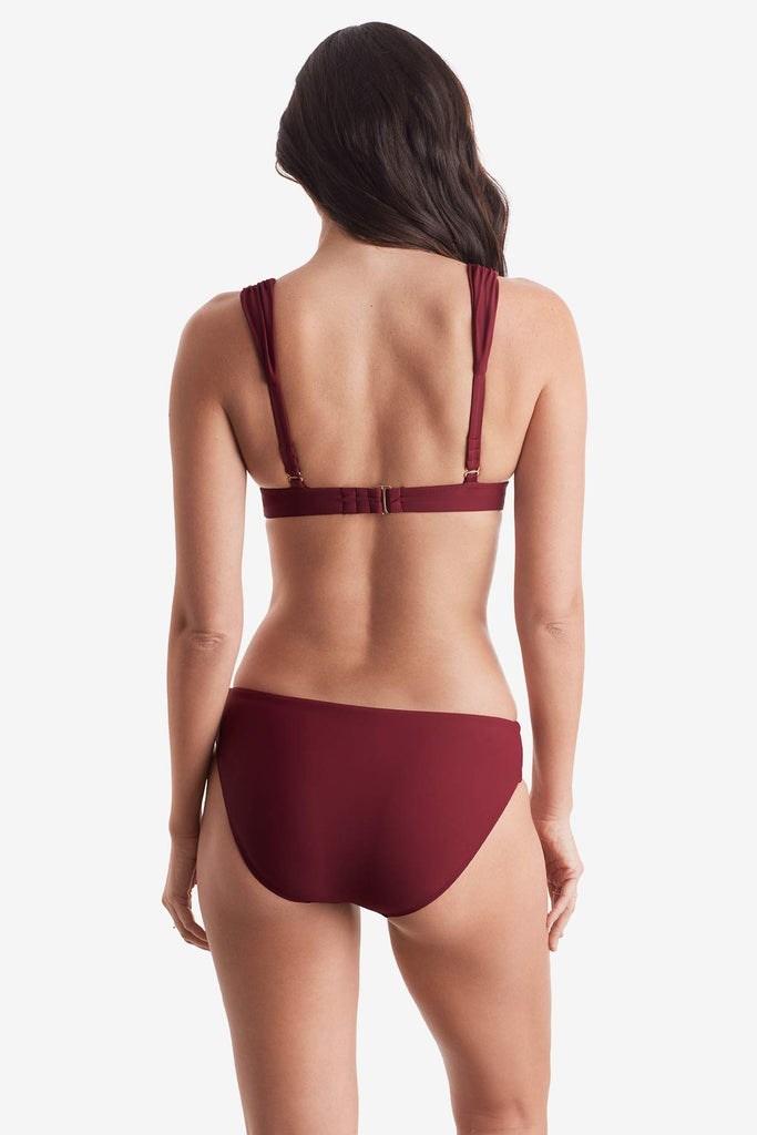 Woman turned away wearing a dark red bikini top and dark red swim bottoms