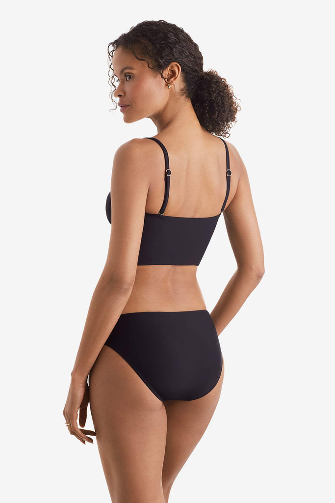 Woman faced left wearing a black midkini swim top with black swim bottoms
