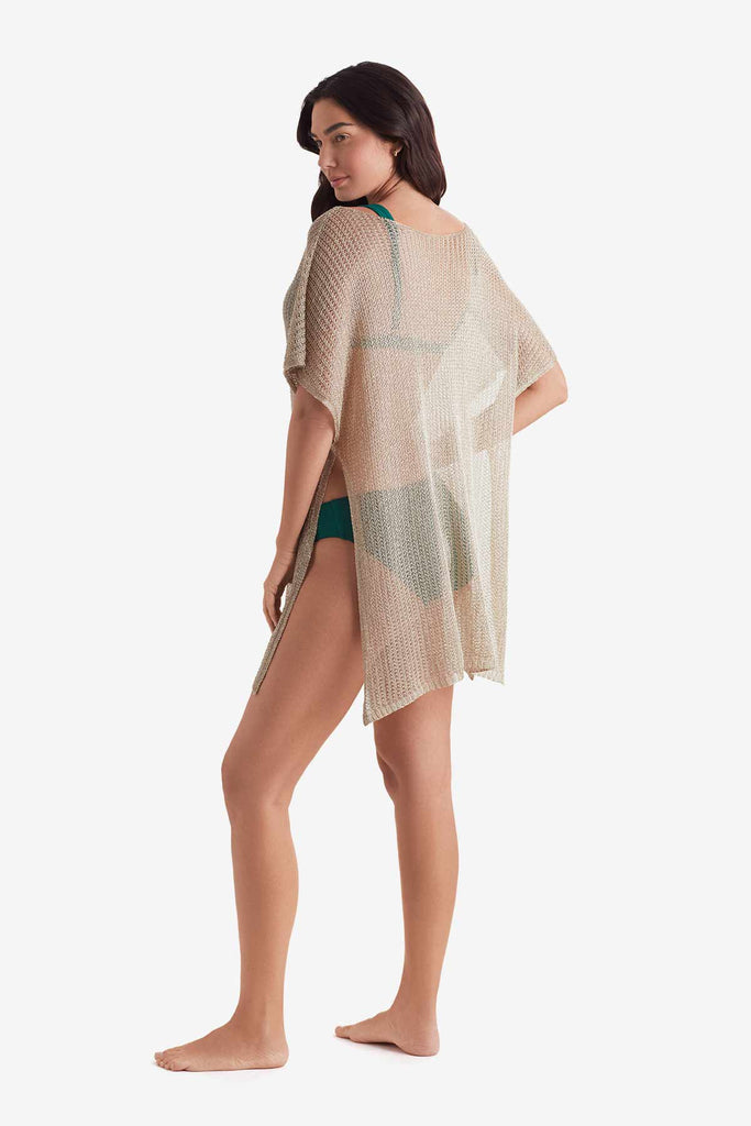 Woman faced left wearing a tunic swim dress cover up in metallic gold