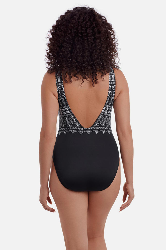 Woman turned away wearing a black and white tribal printed one-piece swimsuit with a deep scoop back 