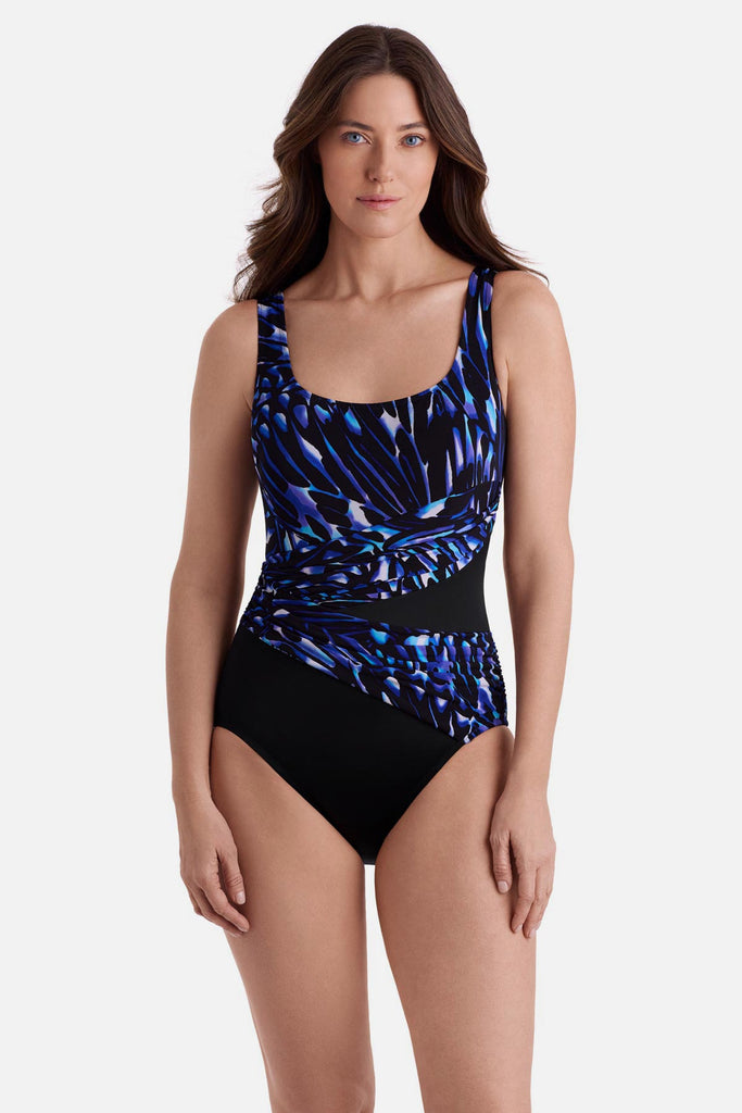Woman wearing a blue abstract printed one-piece swimsuit with black color blocking