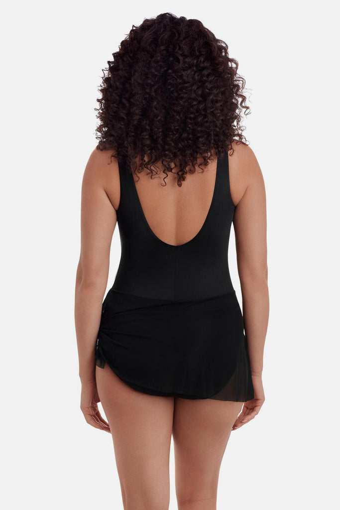 Woman turned away wearing a black one-piece swimsuit with a black wrap sash around the waist