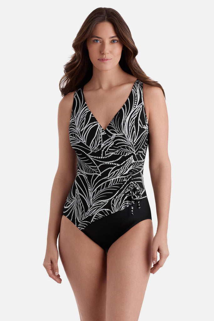 Woman wearing a black and white fern printed swimsuit with a side tie