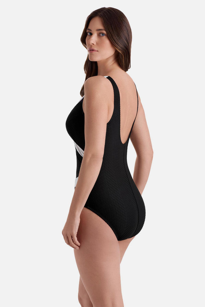 Woman turned left wearing a black one-piece swimsuit with white textured trim