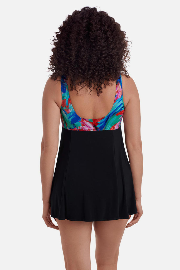 Woman turned away wearing a swim dress with a multicolor abstract pattern across the straps