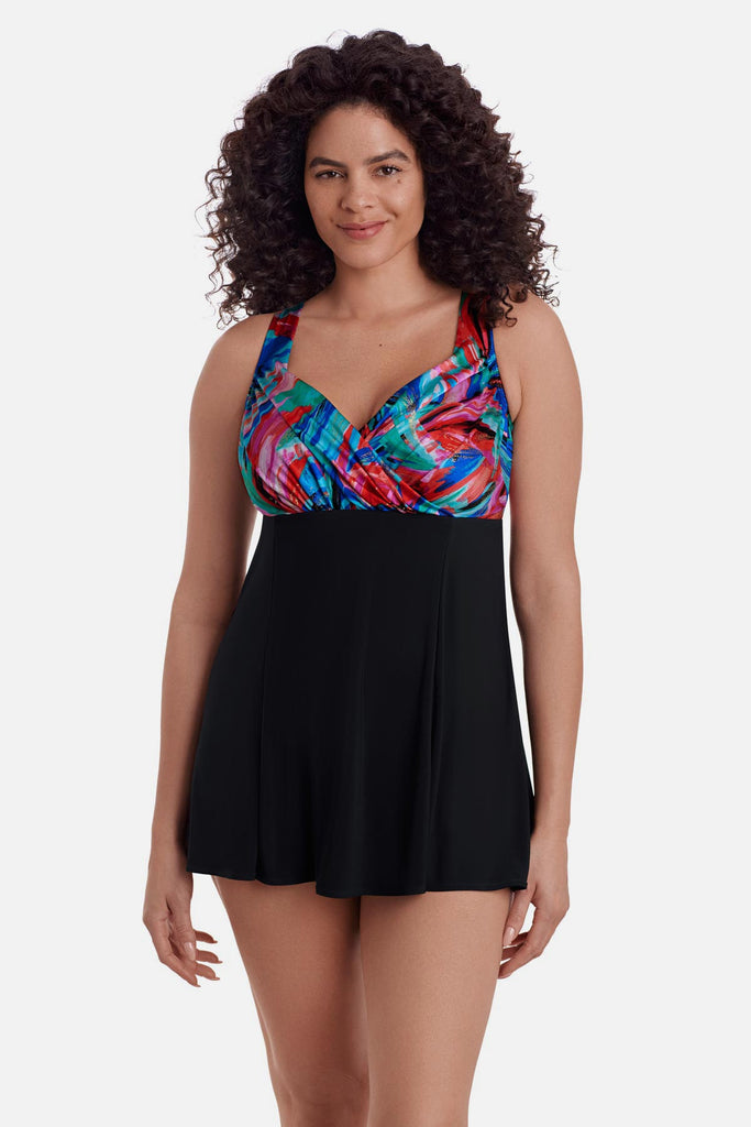 Woman wearing a swim dress with a multicolor abstract pattern across the bust and straps