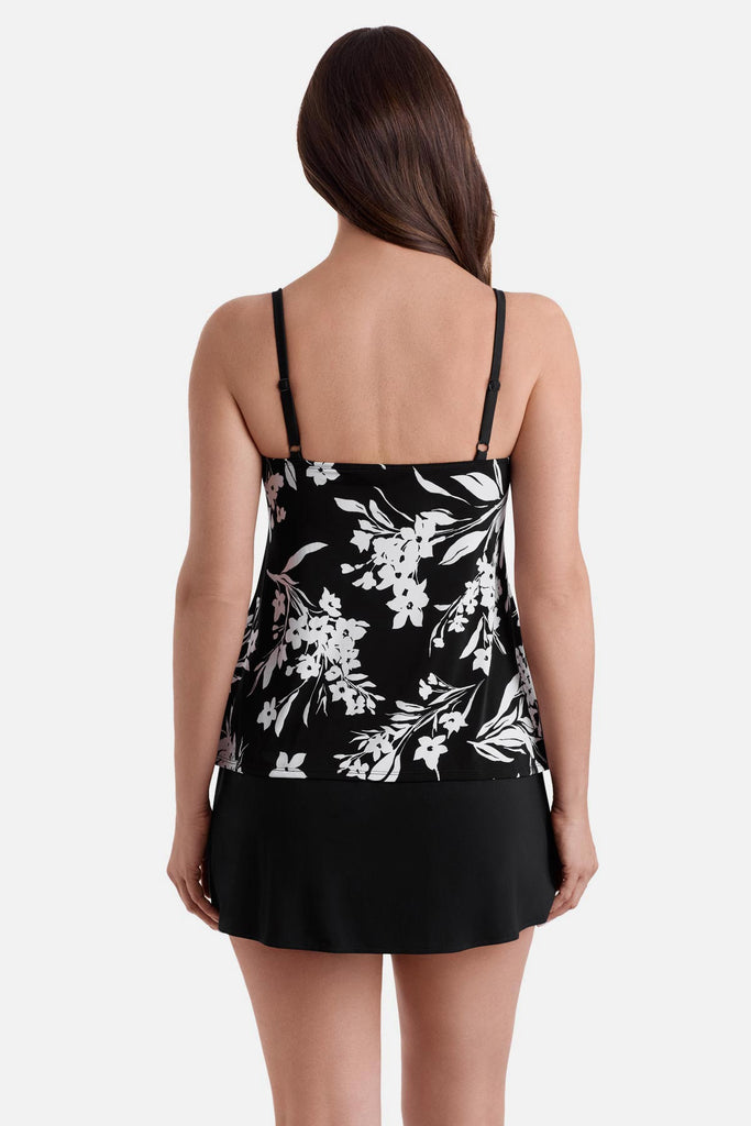 Woman faced away wearing a black and white floral printed ruffle skirtini swimsuit
